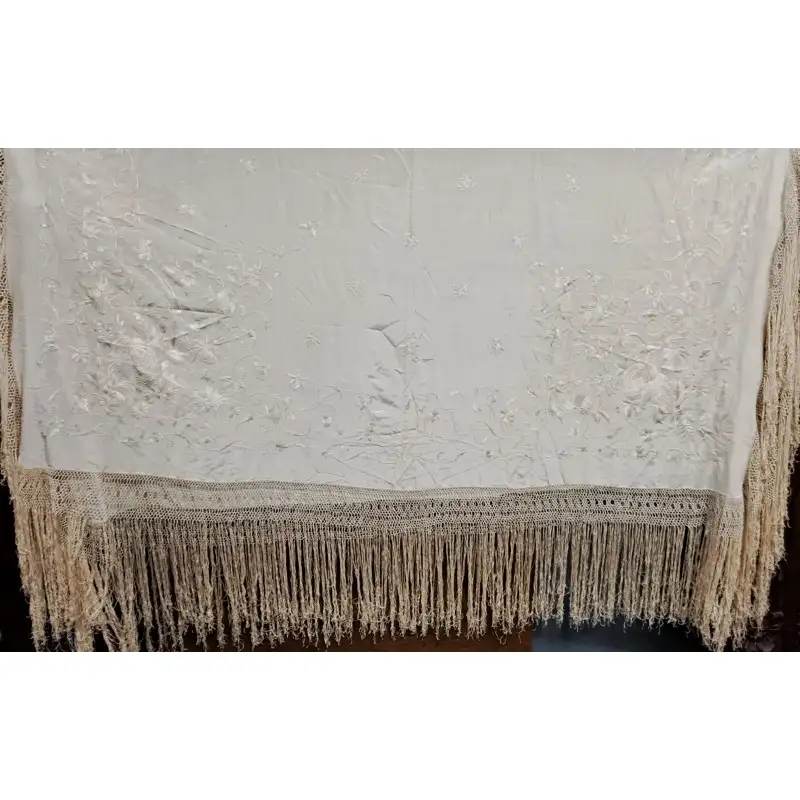 Mantón de Manila en seda marfil bordada con flores y flecos anudados